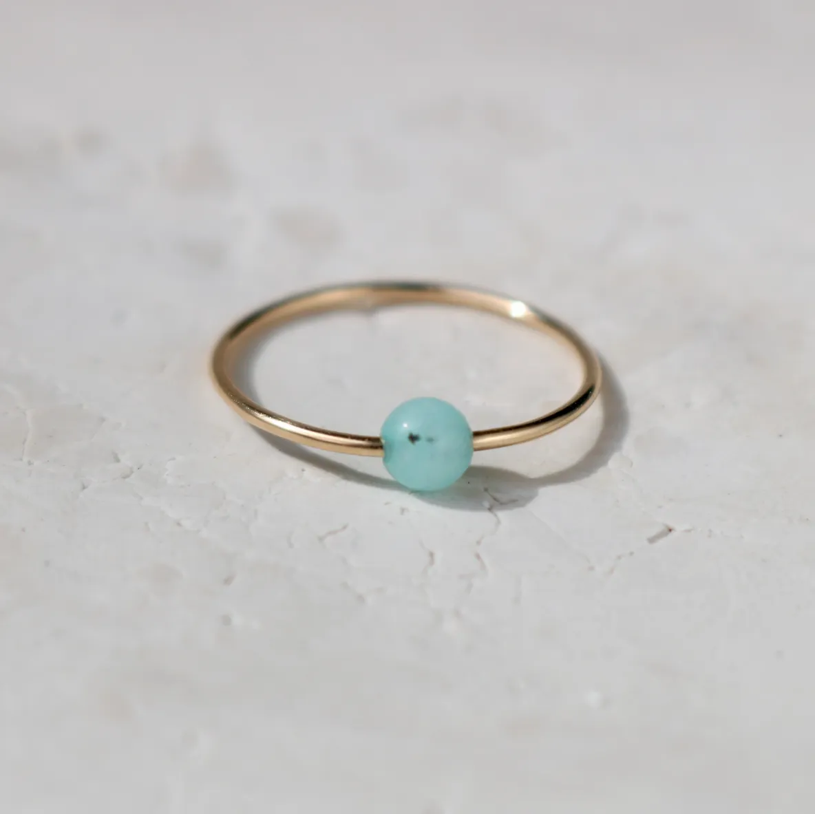 Gold ring with a small turquoise bead.